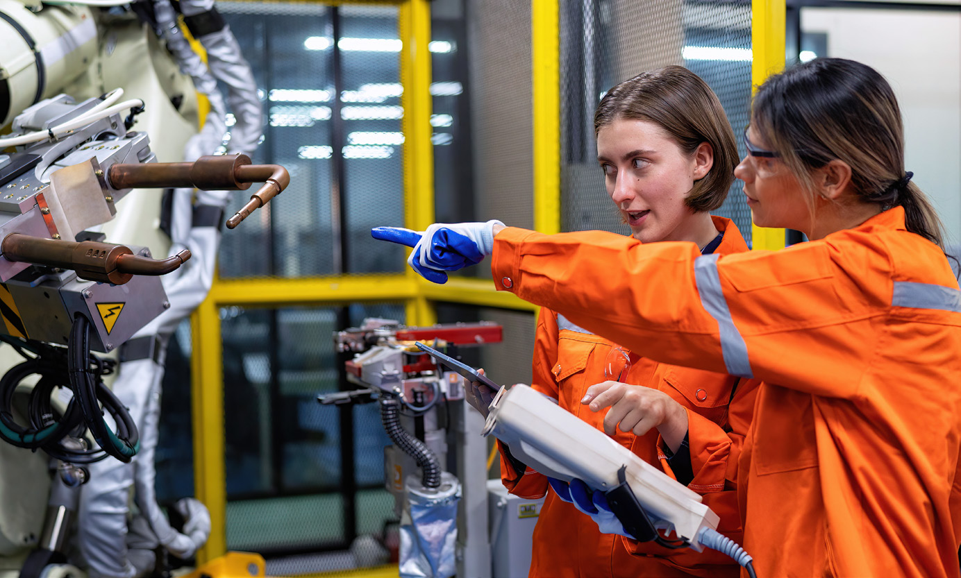 Two women pointing at machine
